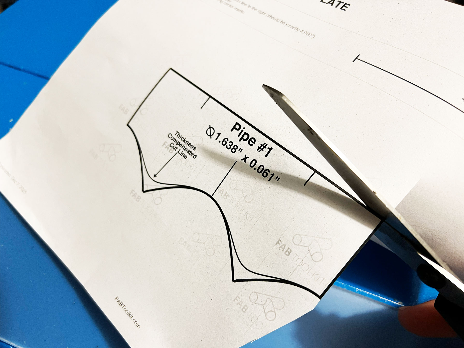 Cutting out a printed tube coping template with scissors